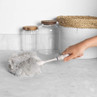 White microfibre duster with handle cleaning kitchen counter near storage jars