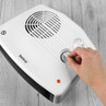 White fan heater with hand adjusting the dial, suitable for home use