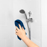 Hand cleaning shower tiles with blue cloth