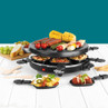 Tabletop raclette grill with assorted vegetables, meats and small serving pans
