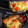 Raclette grill tray with melted cheese and chopped red pepper, Giles & Posner branding visible.