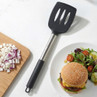 Black and silver slotted spatula next to chopped onion and cheeseburger meal