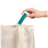 Hand placing compact blue and white folding bag on beige fabric tote