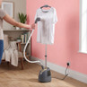 Upright clothes steamer in use on white t-shirt, showing steam removing creases.
