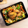Roast chicken in black roasting tin with carrots, leeks, parsnips and garlic