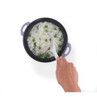 Cooked white rice with green peas in a purple pot, person stirring with a white spoon