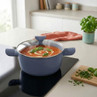 Blue non-stick casserole pot with glass lid, shown cooking tomato soup on a hob.