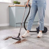 Cylinder vacuum cleaner in use on kitchen floor, cleaning up coffee grounds