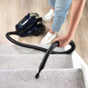 Navy cylinder vacuum cleaner in use on carpeted stairs