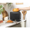 Black metal bread bin with lid open, loaf inside, on modern kitchen counter