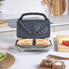 Grey sandwich toaster with two toasted sandwiches on kitchen counter