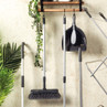 Set of grey cleaning tools on wall rack, including broom, dustpan and brush, and mop handle