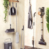 Set of grey cleaning tools and cordless vacuum displayed against wall in home