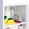 Set of cleaning sponges and a scrubbing brush with pink bristles in a white cupboard