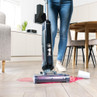 Hand removing dirty water tank from upright cordless vacuum cleaner.