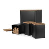 Set of black metal kitchen storage canisters with wooden lids, shown with sugar cubes inside one.