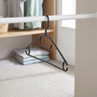 Black plastic clothes hanger with hooks, hanging on a wardrobe rail