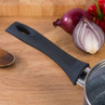 Black soft-touch saucepan handle, close-up, with onion and pepper in background