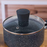 Black non-stick saucepan with glass lid on wooden kitchen surface
