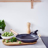 Black non-stick frying pan with wooden handle on kitchen counter