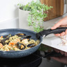 Non-stick frying pan with detachable handle on hob, cooking seafood pasta