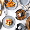 Grey non-stick cookware set with food, including frying pan, saucepan, and grill pan