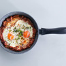 Frying pan with baked eggs in tomato sauce, viewed from above