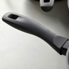 Grey non-stick saucepan with soft-touch black handle, close-up showing cooked food inside.