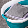Folded clothes in turquoise and white laundry basket on grey carpet