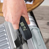 Hand using digital luggage scale on silver suitcase