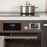 Silver digital kitchen timer on oven next to a saucepan, showing zero minutes