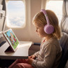 Child wearing pink headphones watching cartoon on tablet in airplane seat
