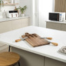 Wooden carving board with three knives, shown on a kitchen worktop