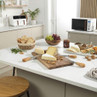Kitchen counter with assorted cheeses, bread, grapes, chutney and cheese knives arranged for serving