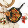 Non-stick frying pan with crispy chicken thighs, roasted vegetables, and tomatoes