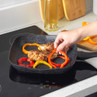 Granite-effect square frying pan with grilled chicken and sliced peppers, on hob.