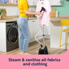 Woman steaming a pink T-shirt on garment steamer, with text 'Steam & sanitise all fabrics and clothing'