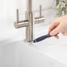 Hand cleaning around the base of a kitchen tap with a small brush