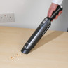 Cordless handheld vacuum cleaning crumbs on a light wood table