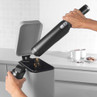 Handheld cordless vacuum cleaner being emptied into kitchen bin