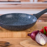 Non-stick blue speckled frying pan with black handle on kitchen counter