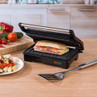 Black panini press with toasted sandwich in kitchen setting