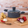 Black speckled non-stick stock pot with glass lid on kitchen counter, vegetables displayed