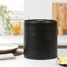 Black ribbed metal bread bin with lid on a kitchen counter