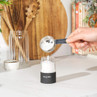 Hand measuring salt over electric grinder in modern kitchen setting