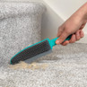 Hand using a rubber brush to remove pet hair from grey carpeted stairs