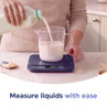 Person pouring milk into a measuring jug on digital kitchen scales