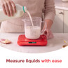 Milk being poured into a measuring jug on red digital kitchen scales