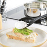Poached egg being served onto avocado toast on white plate in kitchen