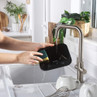 Washing black kitchen scale under tap with sponge, shows easy cleaning feature